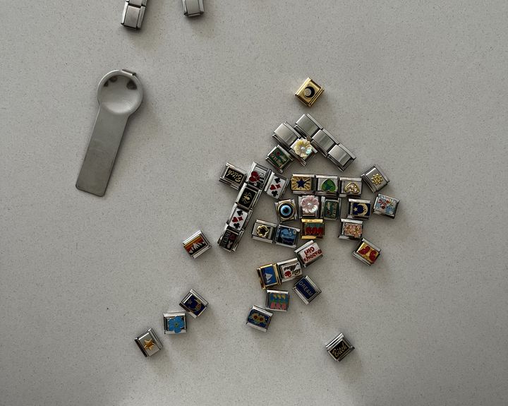 Multiple italian charms and charm tool on white surface