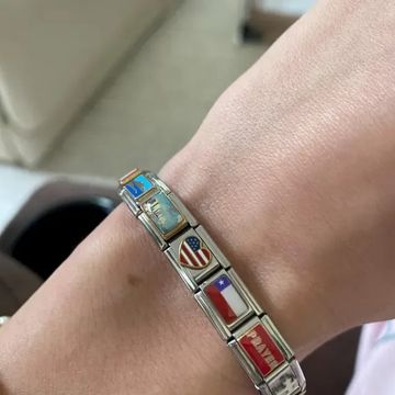 Close up of wrist wearing a Italian charm bracelet with links including the American flag and Chilean flag