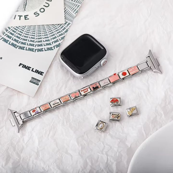 ChatGPT said:  Italian charm bracelet with interchangeable stainless steel links in pink, red, and neutral tones, displayed with an Apple Watch. The bracelet features themed charms including “Daddy’s Girl,” a heart, a black cat silhouette, and playful motifs. Additional loose Italian charm links with designs like a red car, pearl accent, coffee cup, and gold key are arranged beside the bracelet on a white textured surface.