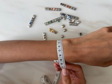 Women measuring wrist with italian charms on the background