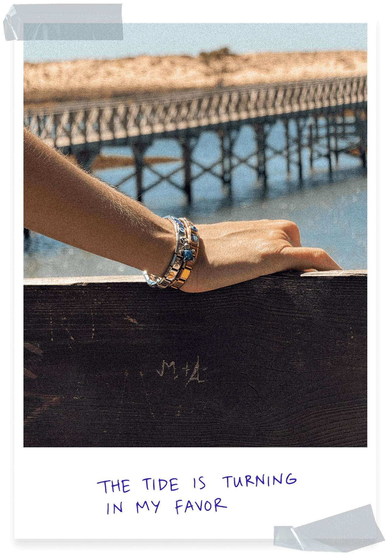 Woman wearing stacked Italian charm bracelets by the sea, featuring silver and gold charms in a vintage coastal setting.